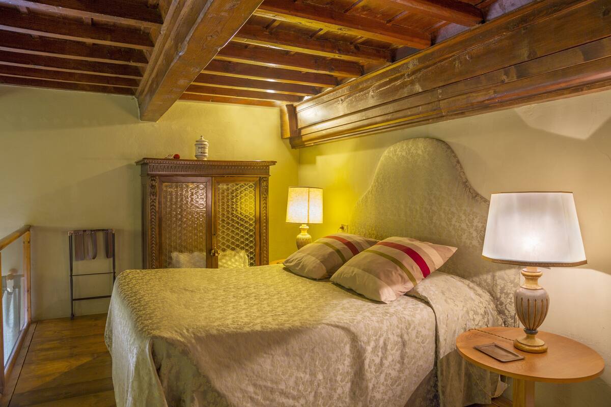 Ein Schlafzimmer mit einem Bett, einem Nachttisch aus Holz, einer Lampe und einem kleinen Tisch.