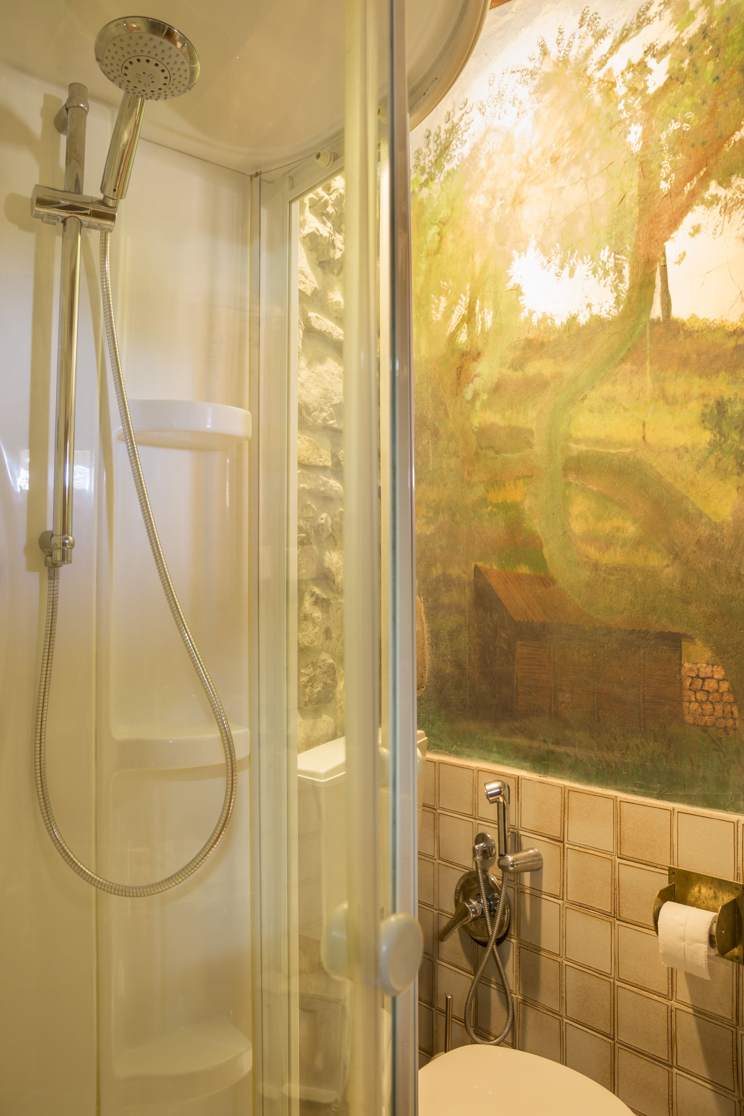 Ein Badezimmer mit Dusche, Toilette und einem Fenster mit Landschaftsblick.