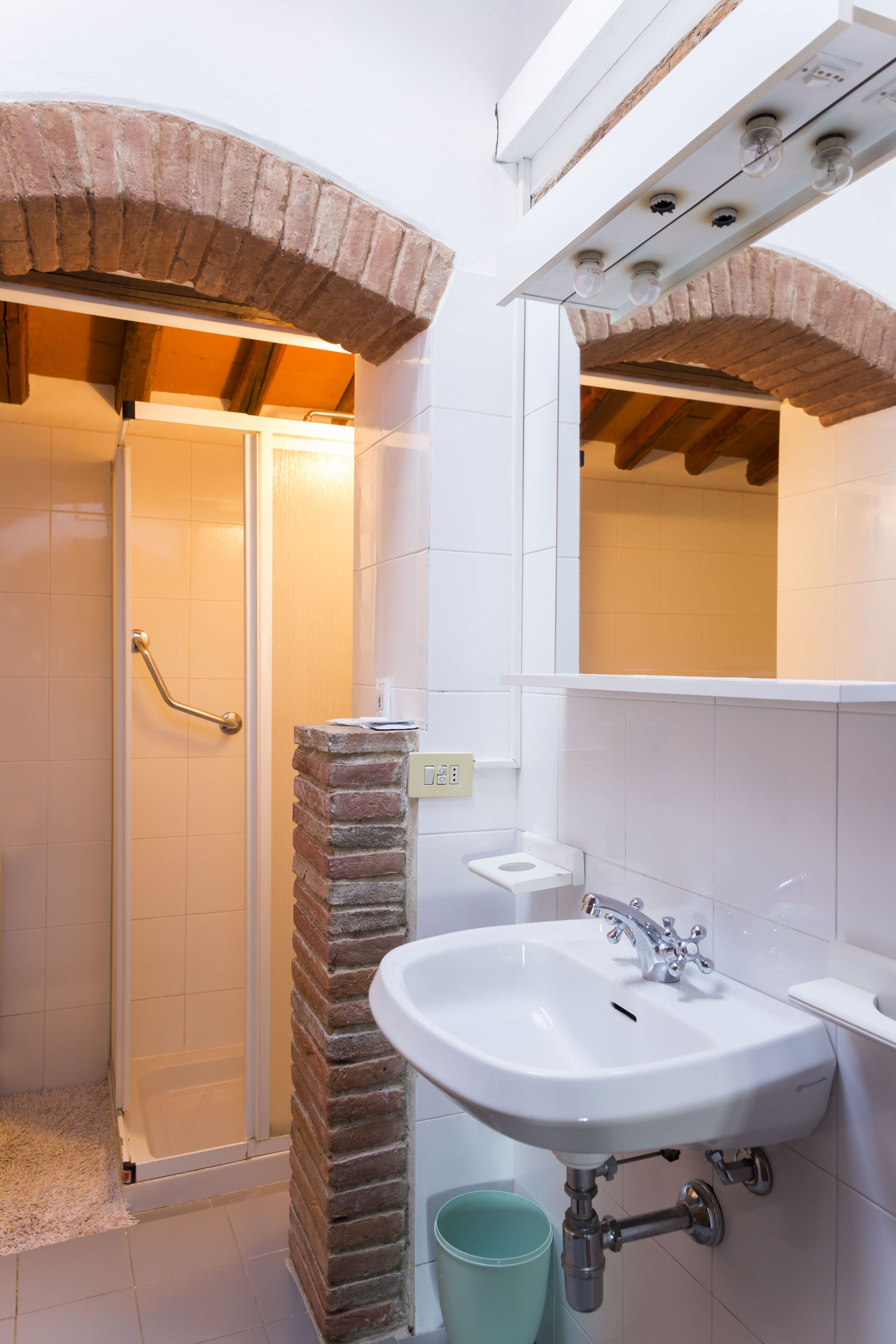 Un baño con ducha, lavamanos y espejo.