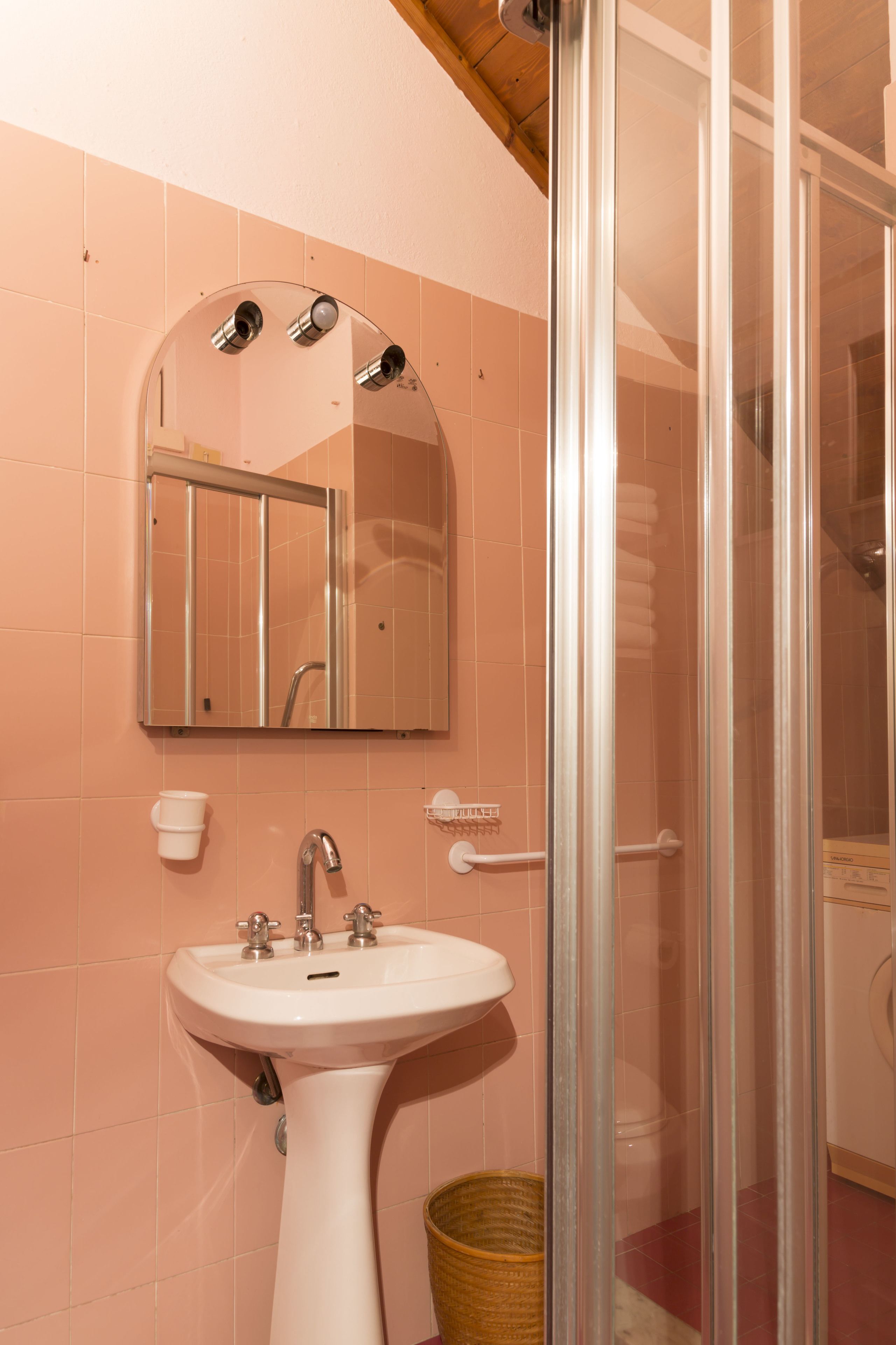 Ein Badezimmer mit einem weißen Waschbecken, einem Spiegel und einer Duschkabine.