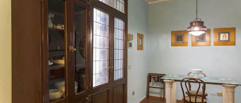 A dining area with a glass-top table, wooden chairs, and a cabinet with glass doors.