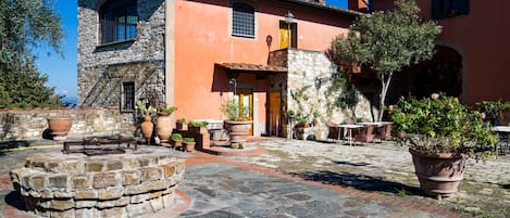 A stone building with a stone staircase and a wooden door. There are potted plants and outdoor furniture.