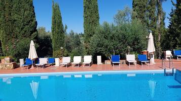 Una piscina al aire libre de temporada, sombrillas