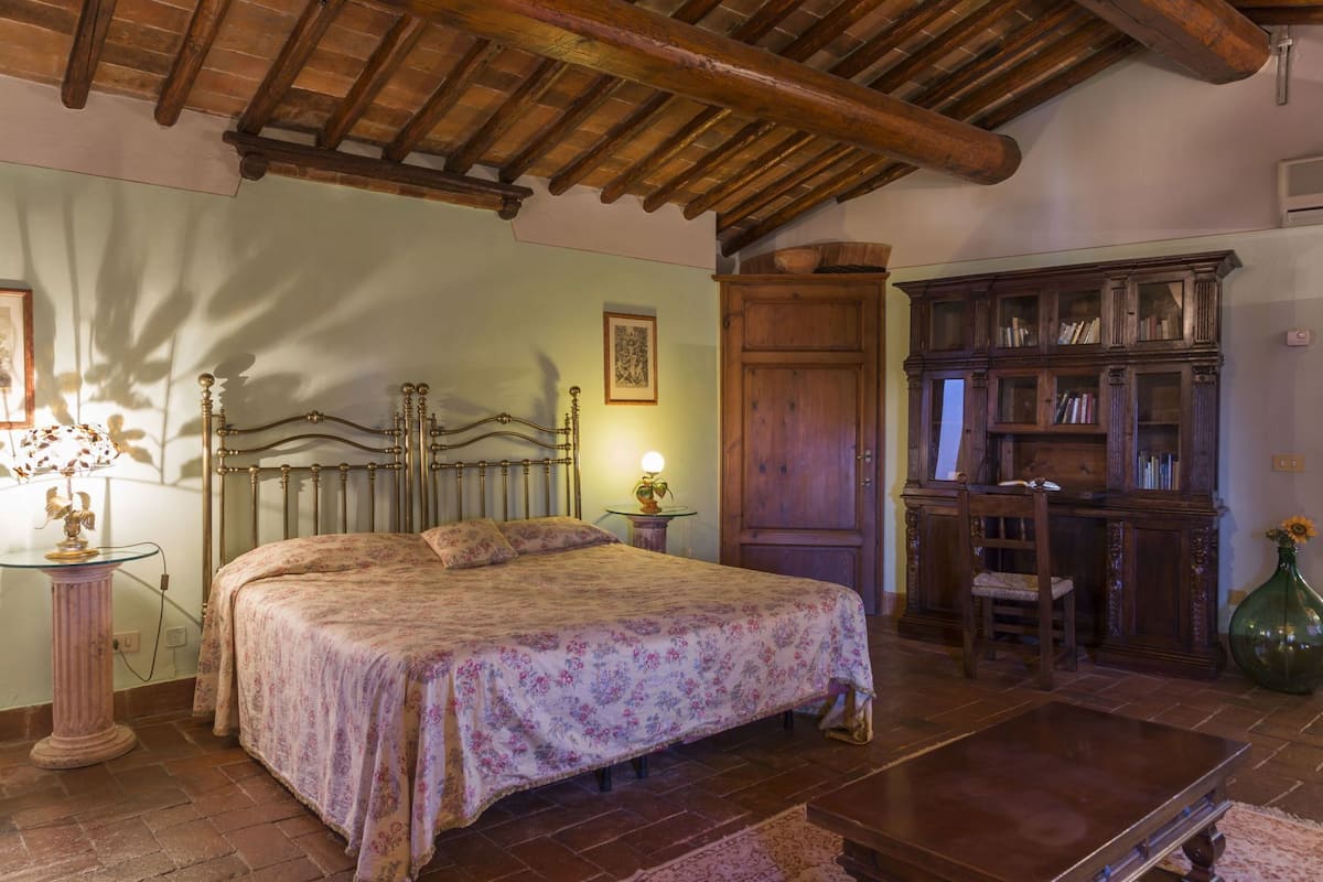 Ein Schlafzimmer mit einem Bett, Holzmöbeln, einem Bücherregal und einer rustikalen Decke.