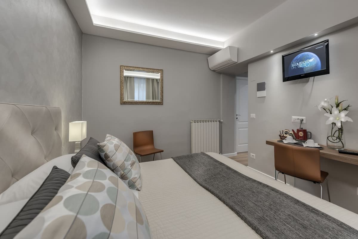 Habitació d'hotel moderna amb llit, escriptori, cadira, televisió i radiador.