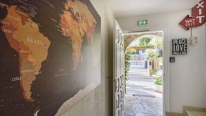 A hallway with a large world map on the wall, a staircase leading to an outdoor area, and a 'Peace Love Rock & Roll' sign. - Hotel & Studios ASTOR (Antibes)