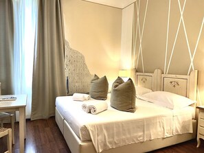 Una habitación de hotel con cama, escritorio y un amplio ventanal con cortinas.