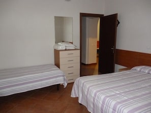 A bedroom with two single beds, a dresser, and a mirror.