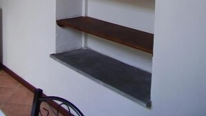 Een hoek met een witte muur en een houten wandplank met drie planken.
