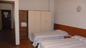 Een slaapkamer met twee eenpersoonsbedden, een kledingkast en een deur naar een andere kamer.