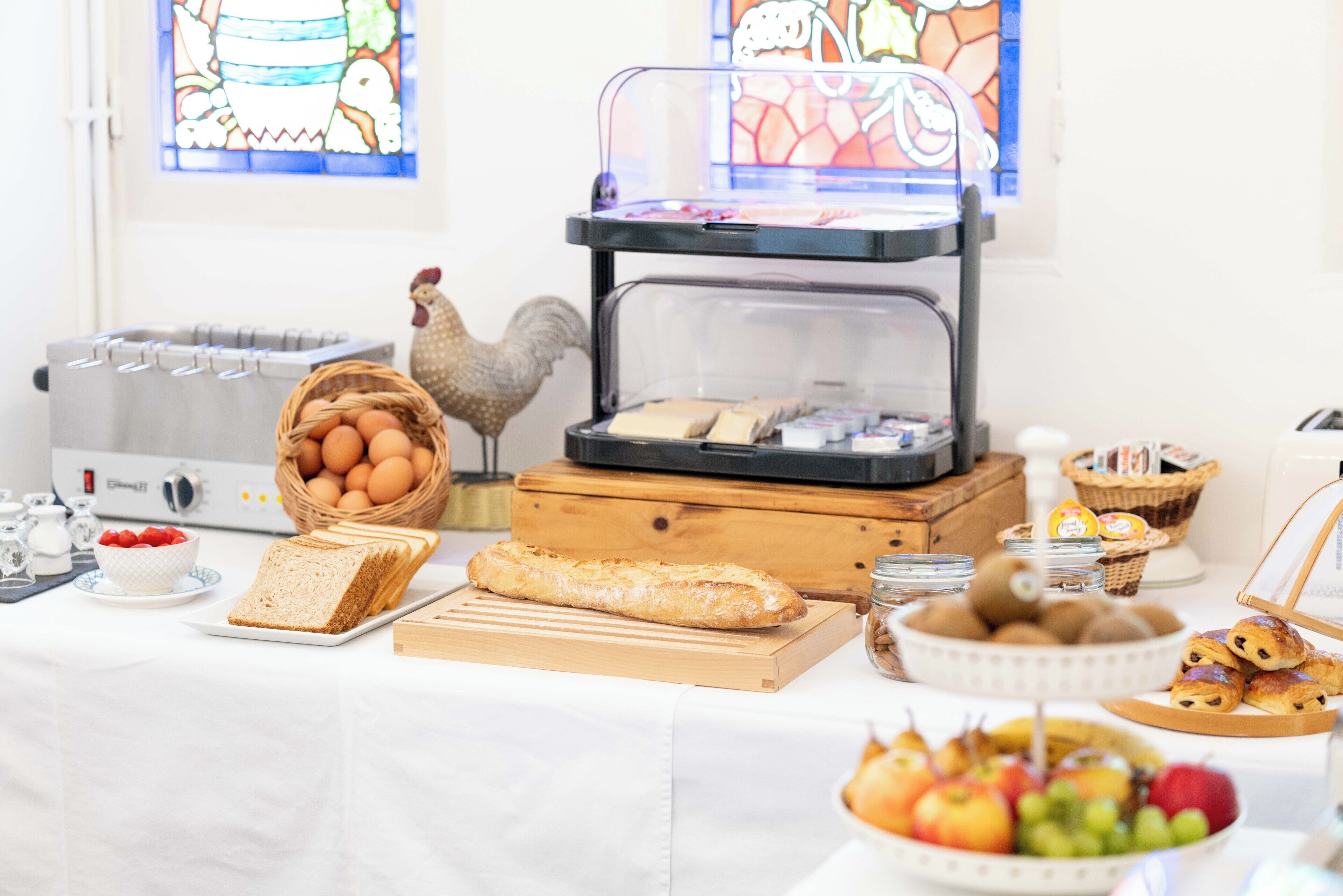 A breakfast buffet with bread, eggs, fruits, and pastries.