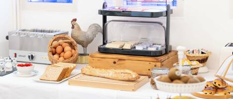 A breakfast buffet with bread, eggs, fruits, and pastries.