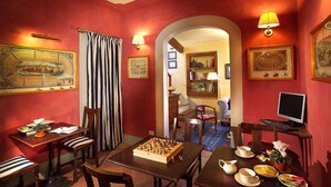 Un comedor con cortinas a rayas, un tablero de ajedrez y un televisor sobre una mesita auxiliar.