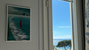 Una habitación con un ventanal grande, un cuadro en la pared y vistas a la calle y a los árboles.
