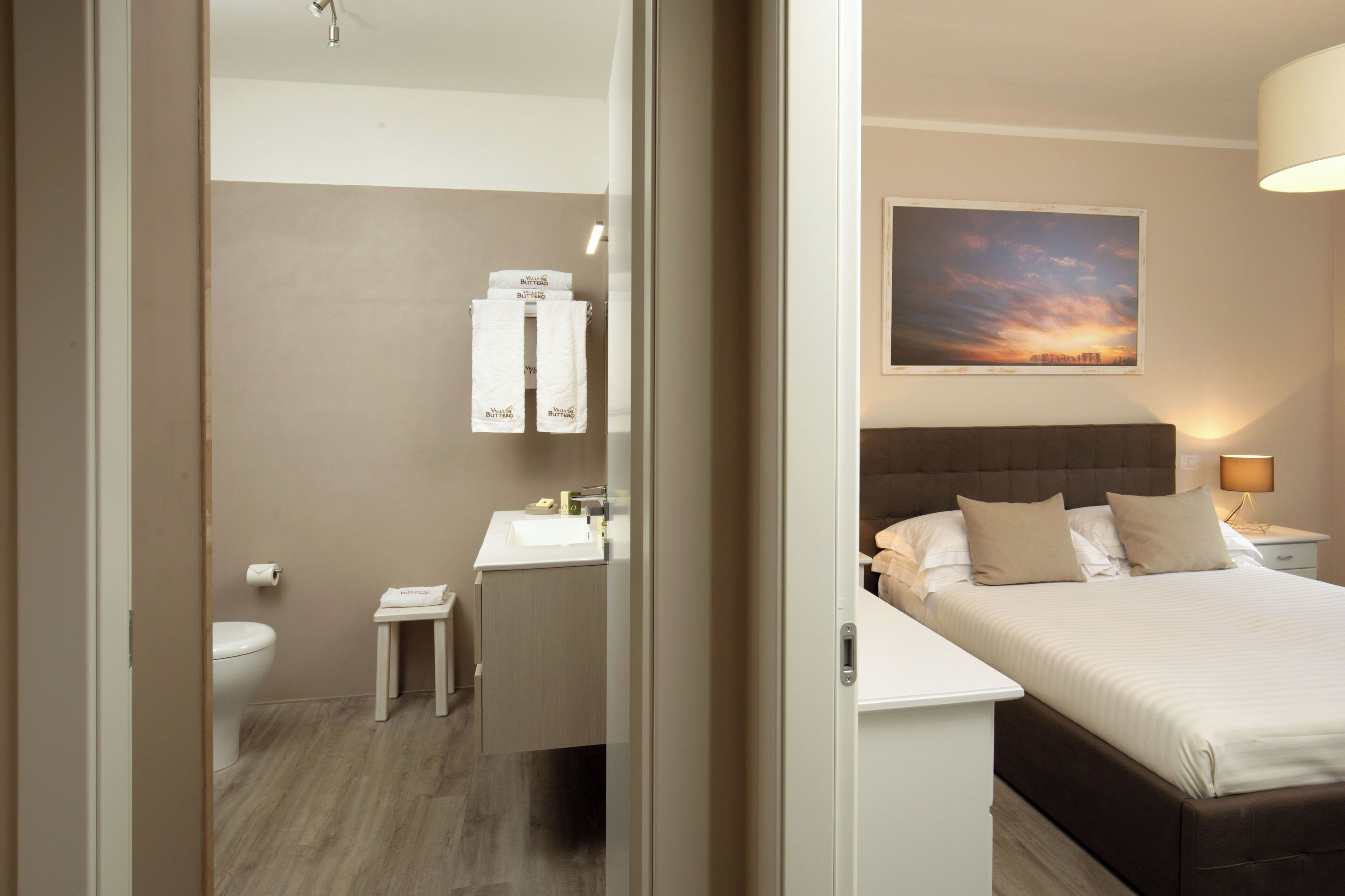 Une chambre d’hôtel avec un lit, une table de chevet et un tableau représentant un coucher de soleil accroché au mur.