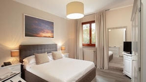 Een moderne hotelkamer met een groot bed, nachtlampjes, een flatscreen televisie en een raam met gordijnen.