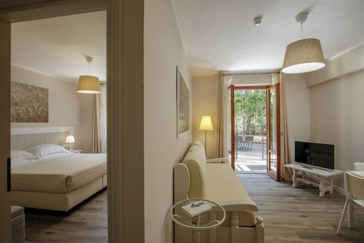 Ein Hotelzimmer mit Bett, Schreibtisch, Fernseher und Blick ins Freie.