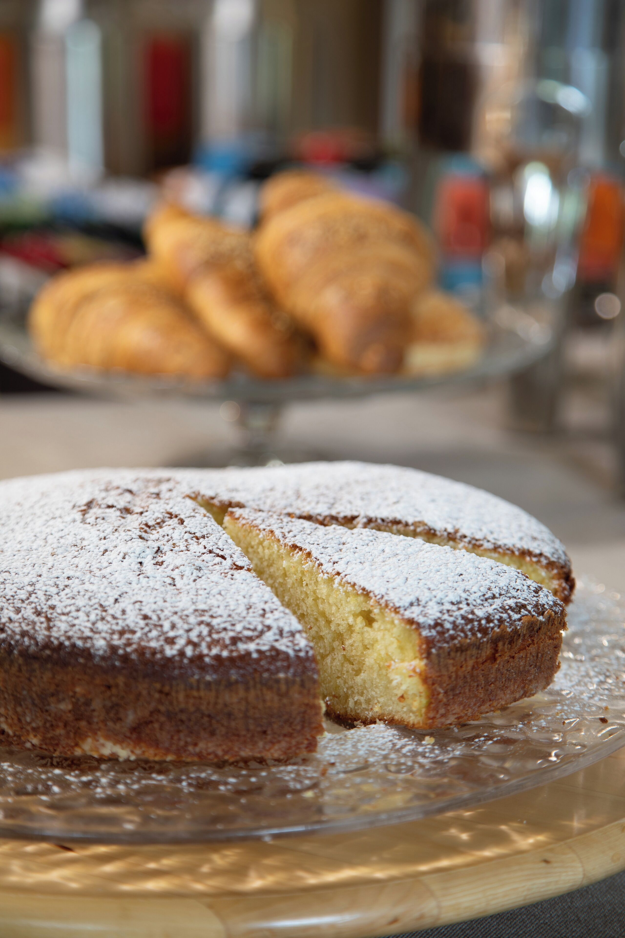 A cake with powdered sugar on a glass plate.
