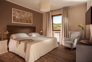 Un dormitorio con una cama grande, una silla, un escritorio y una ventana con cortinas.