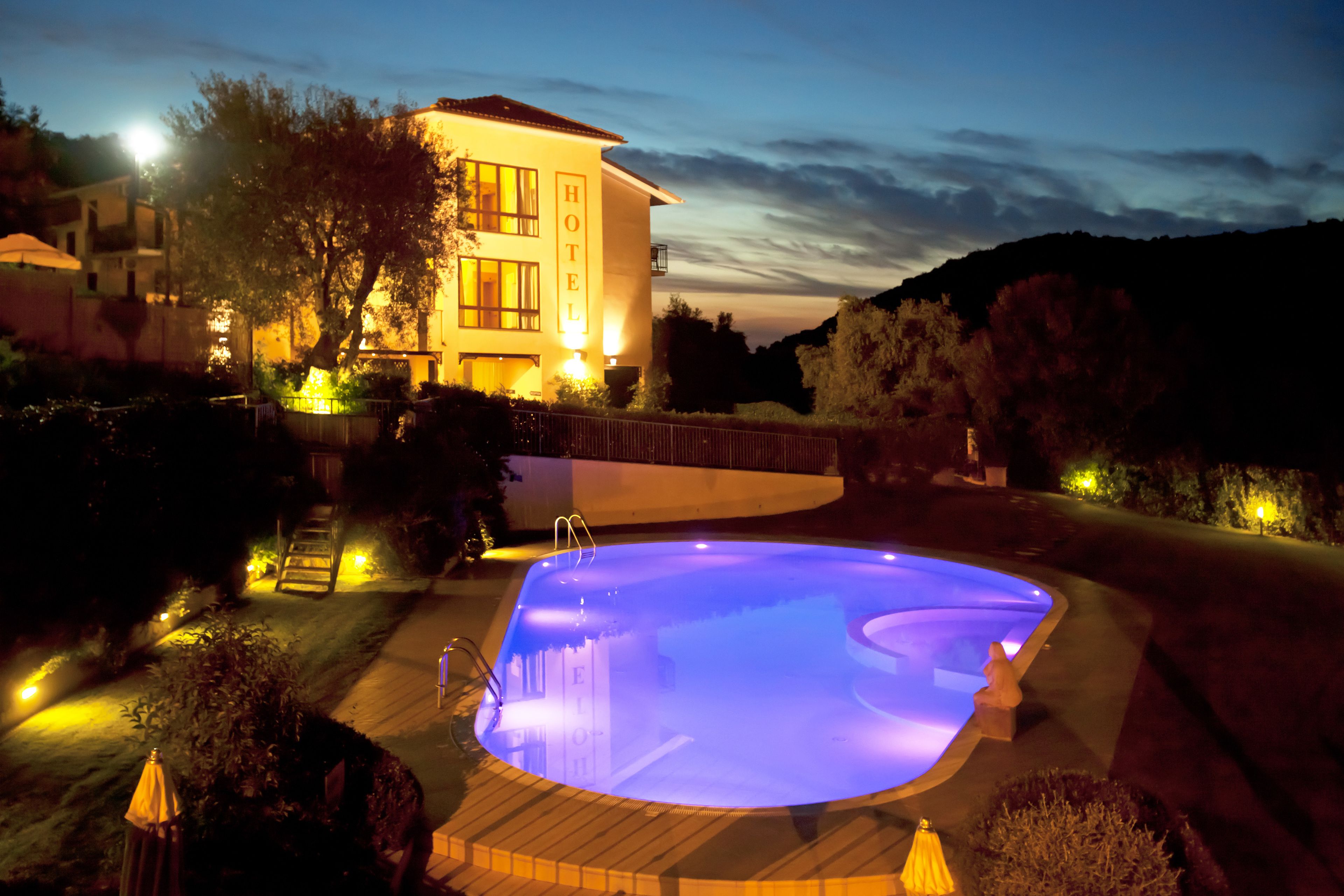 Um hotel com piscina, rodeado por caminhos bem iluminados e jardinagem.