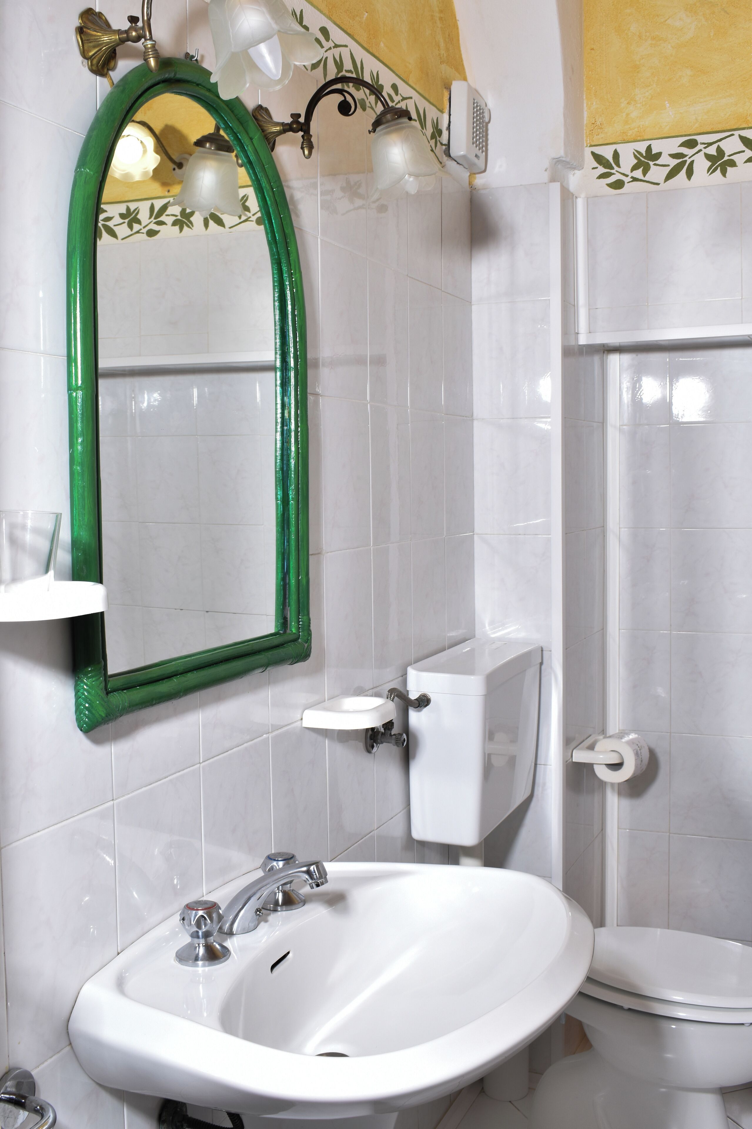 Een badkamer met een wit wastafel, een toilet en een spiegel met een groene lijst.
