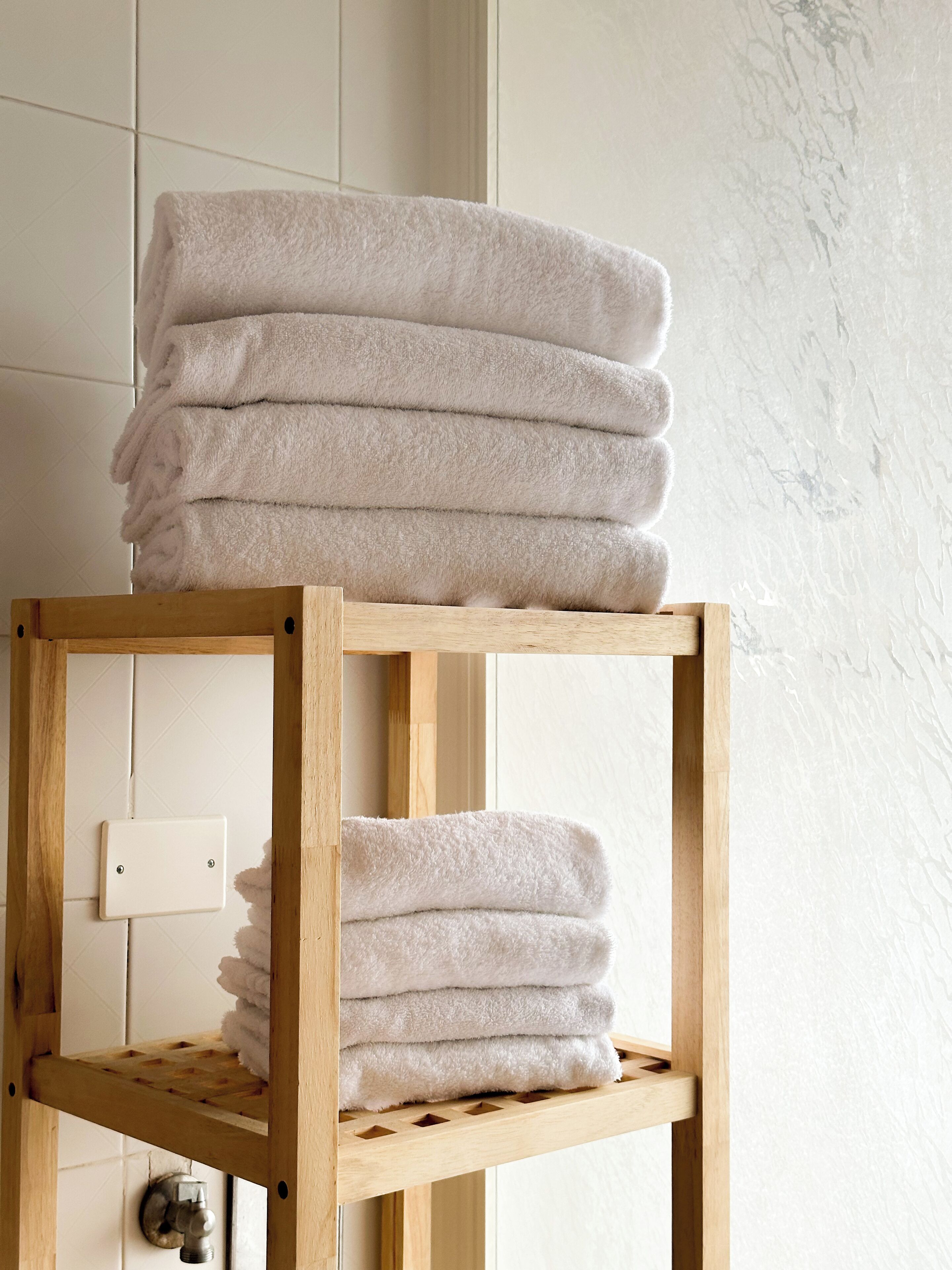 A wooden shelf with folded towels.