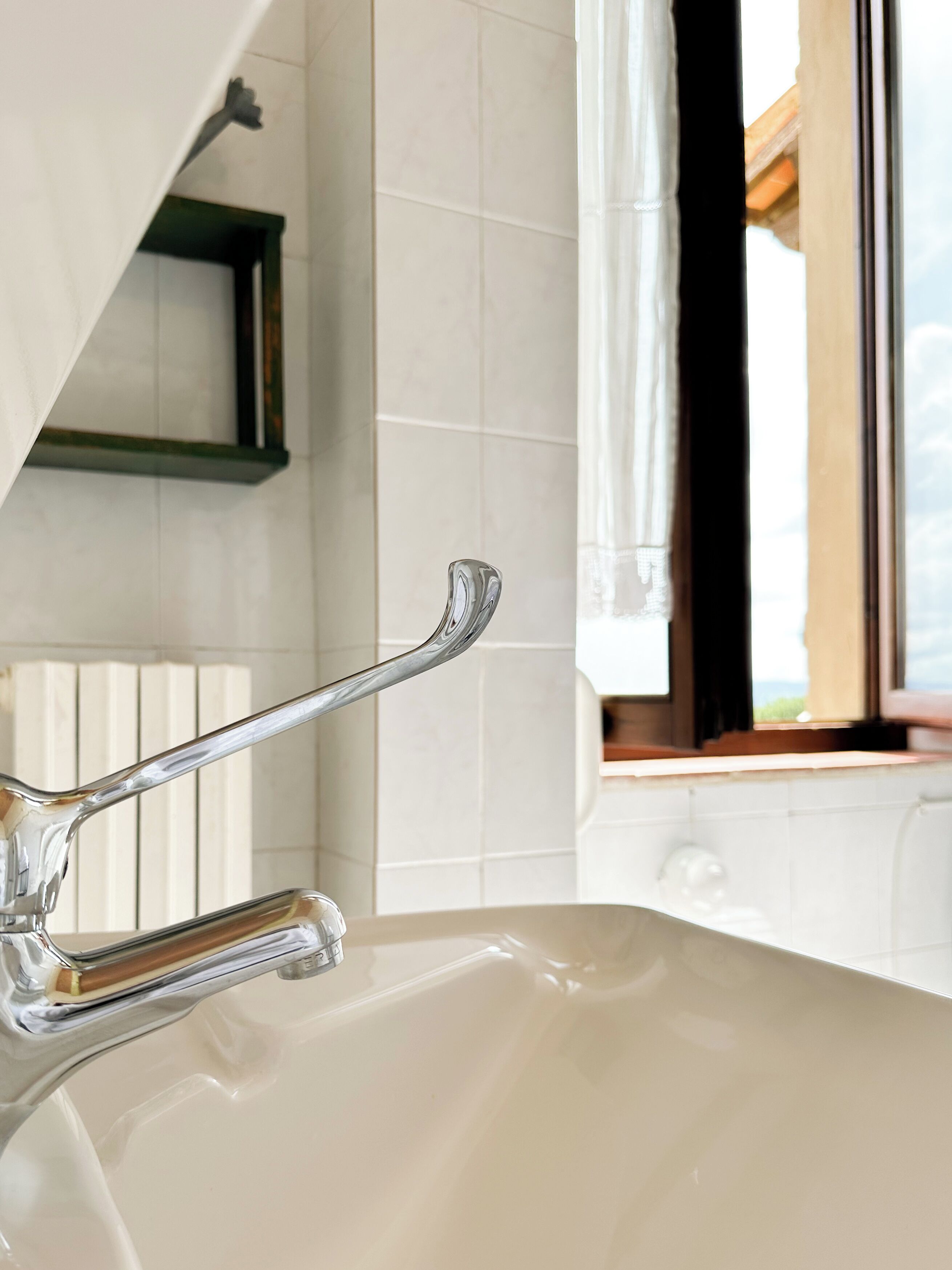 Un baño con un lavamanos moderno, una ventana con vistas y un perchero para toallas.