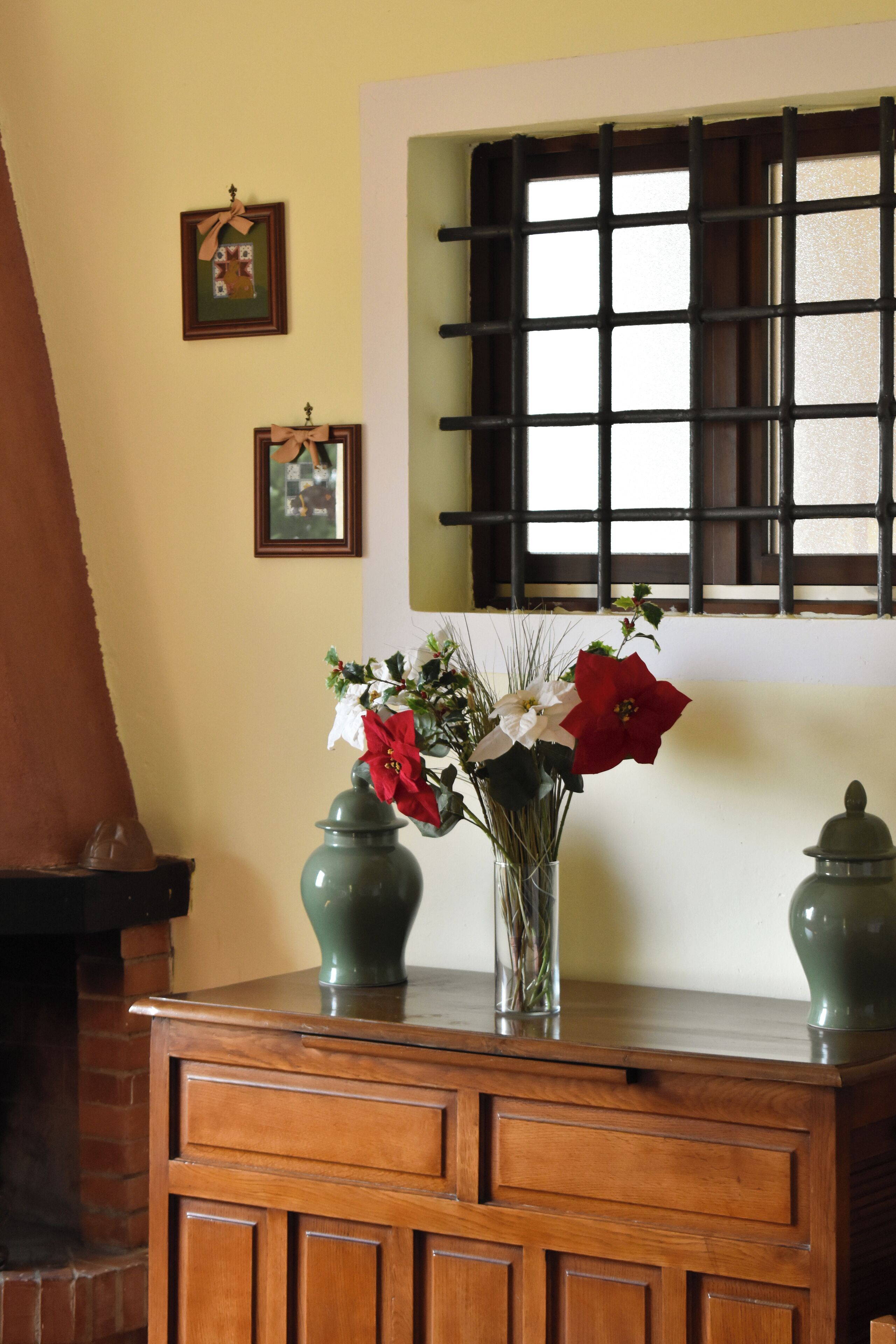 Un mueble de madera con un florero y dos jarrones verdes encima.