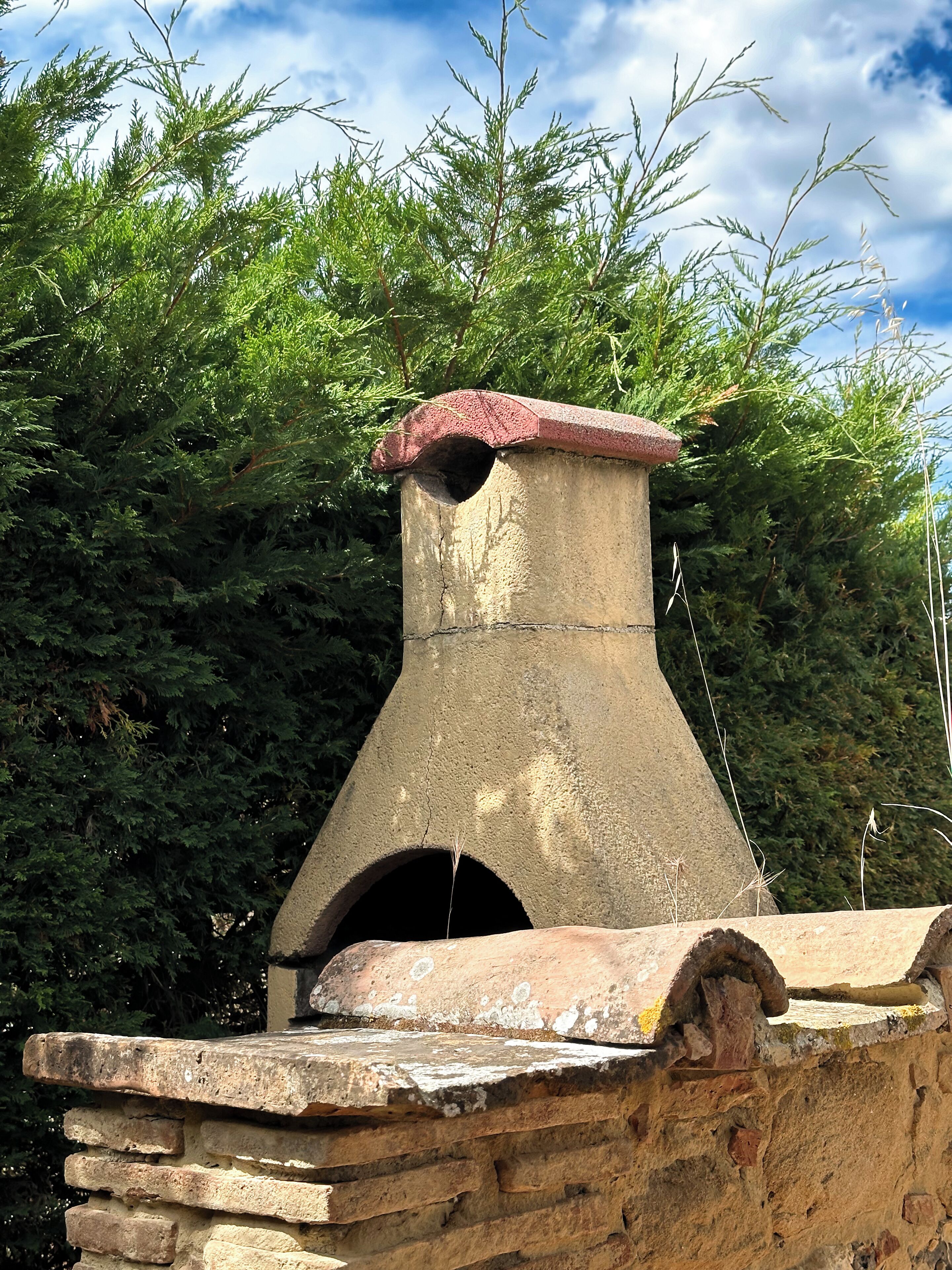 Une structure en pierre surmontée d’une sorte de cheminée, entourée d’un feuillage vert et dense.