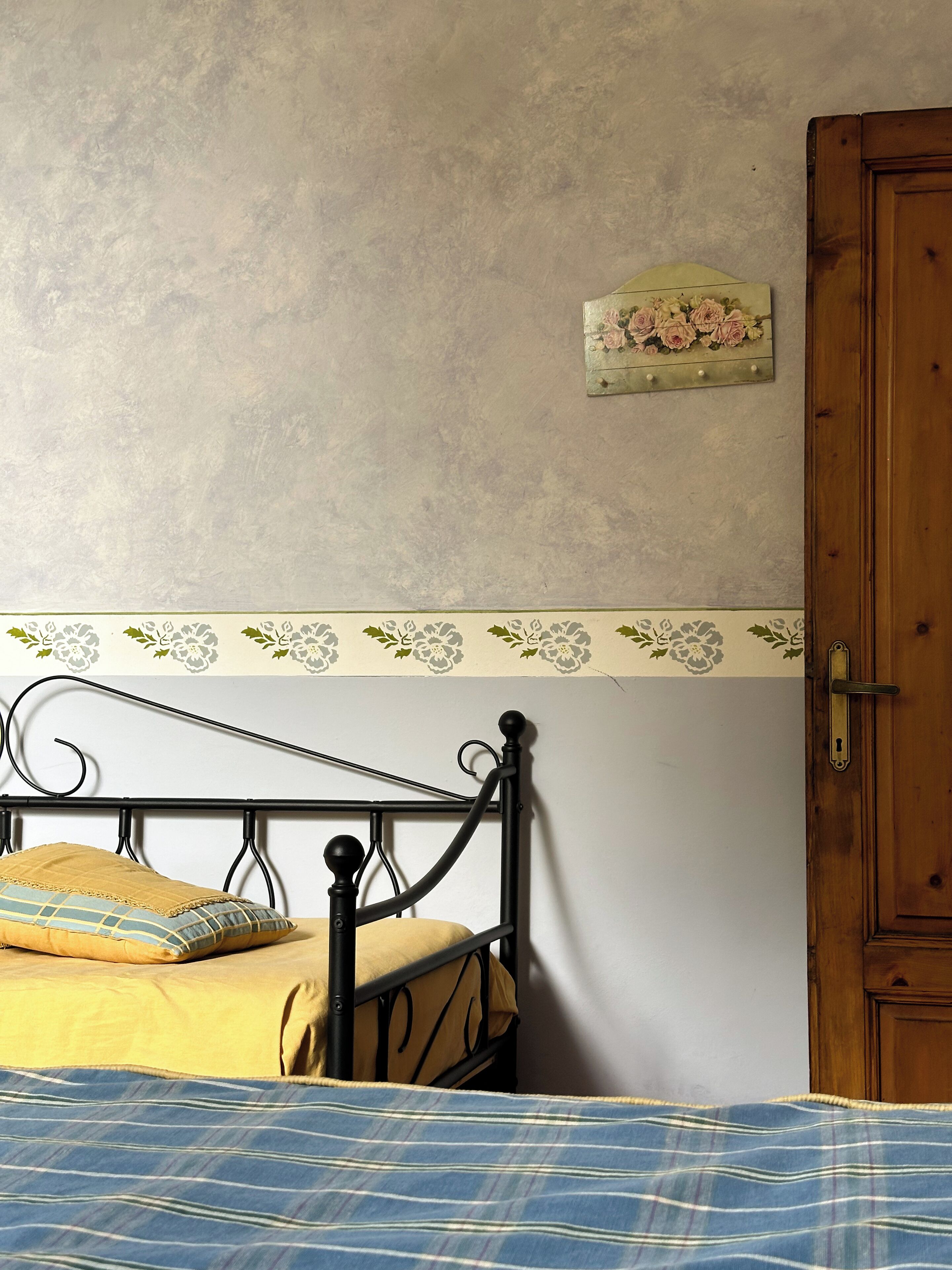 A bed with a metal frame, a yellow bedspread, and a blue striped blanket.