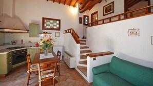 A kitchen with a dining table, chairs, and a green sofa. There is a staircase leading to an upper level. - Podere Poggetto (Barberino Tavarnelle)