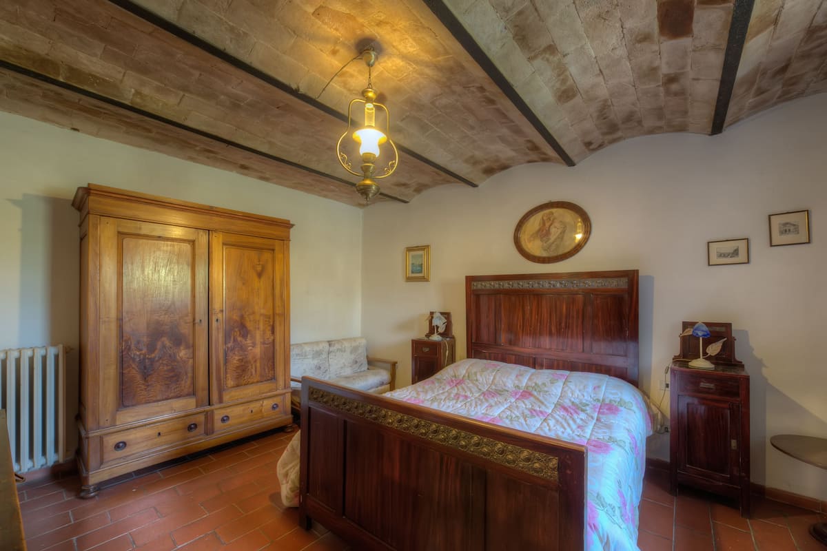 Un dormitorio con una cama de madera, un armario grande y un ventilador de techo.