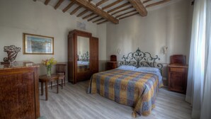 A bedroom with a wooden bed, a wooden dresser, a chair, a mirror, and a painting on the wall. - Podere Poggetto (Barberino Tavarnelle)