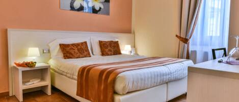 A neatly arranged bedroom with a bed, bedside tables, a desk, and a window with curtains.