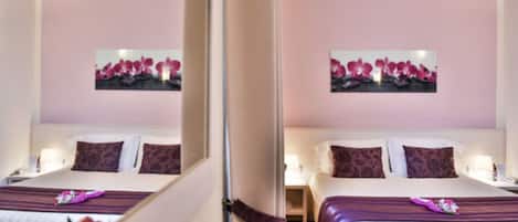 A hotel room with a bed, bedside tables, and a mirror.
