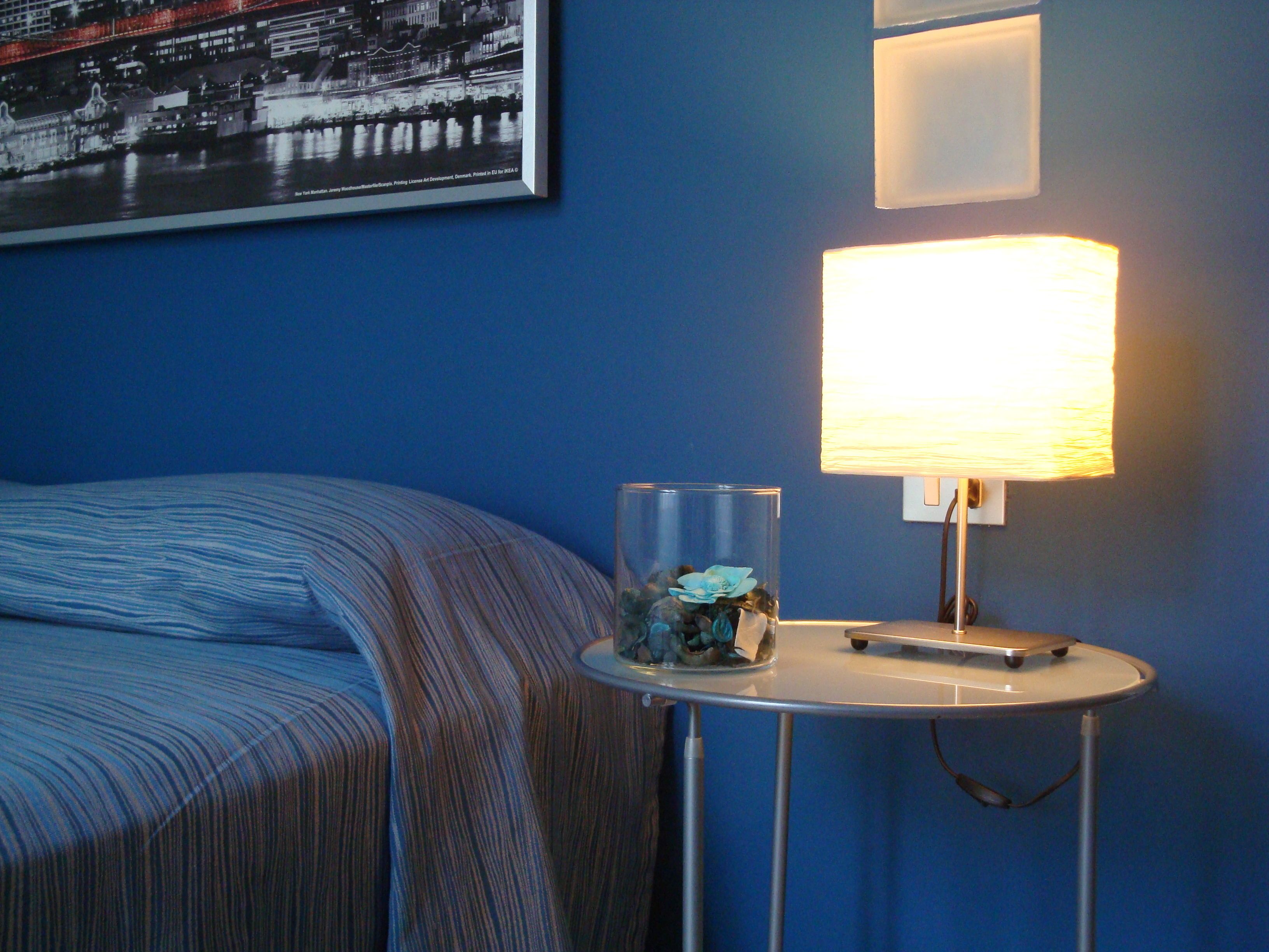 Une chambre d’hôtel avec un lit, une table de chevet avec une lampe et un tableau encadré au mur.