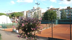 Una cancha de tenis con una red, rodeada por una valla, y un banco al frente.