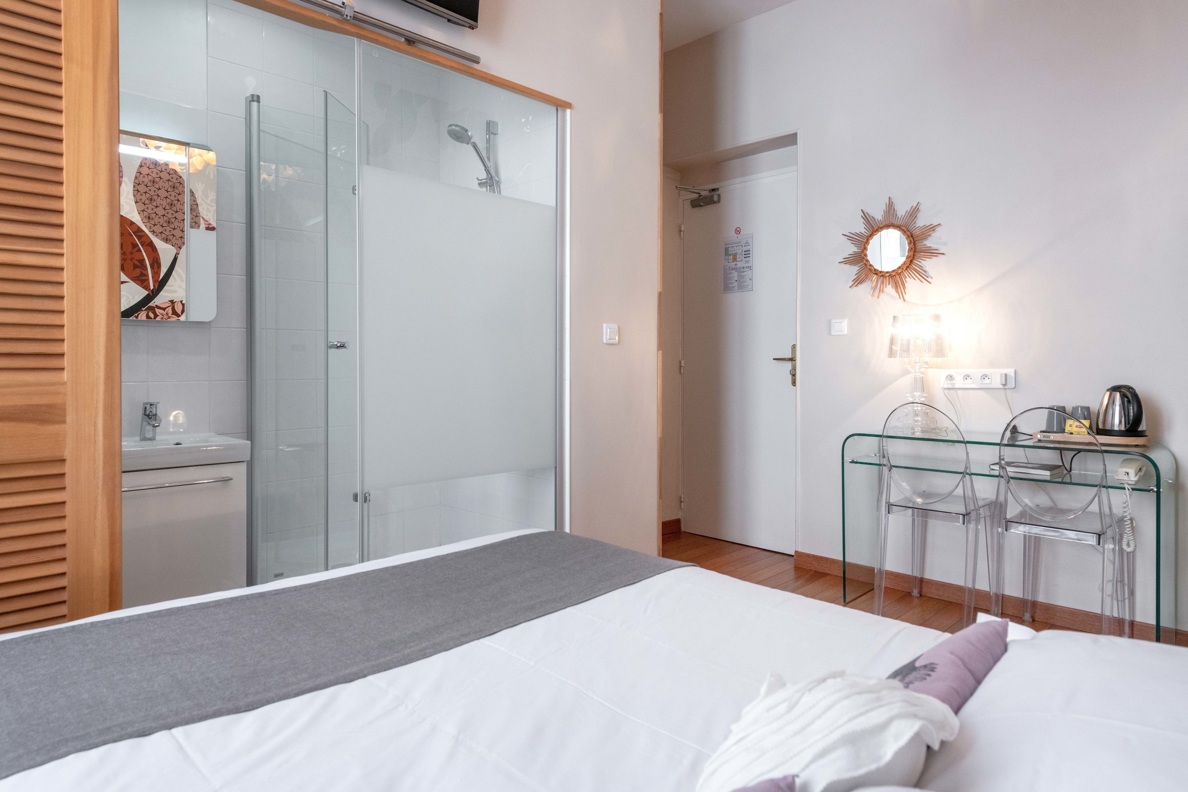 Een moderne slaapkamer met een glazen douche, een nachtkastje met een lamp en een spiegel aan de muur.