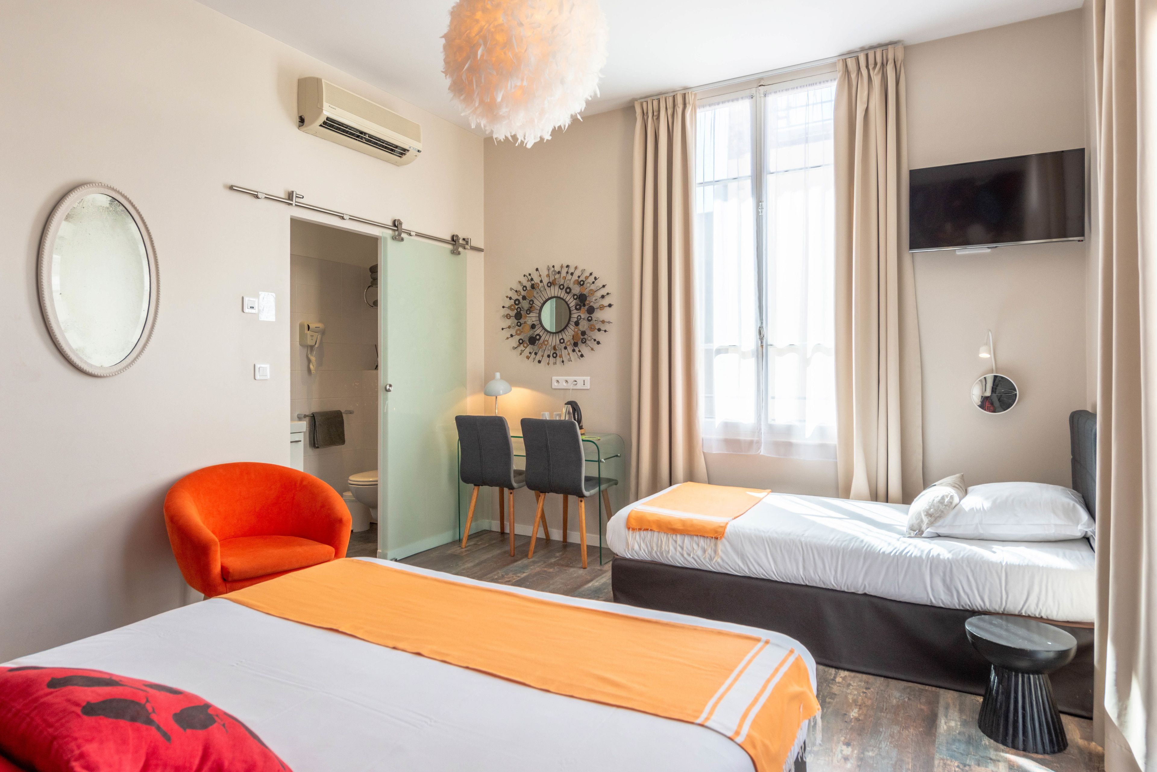 Hotellihuone, jossa on kaksi sänkyä, työpöytä tuoleineen, televisio ja peili.