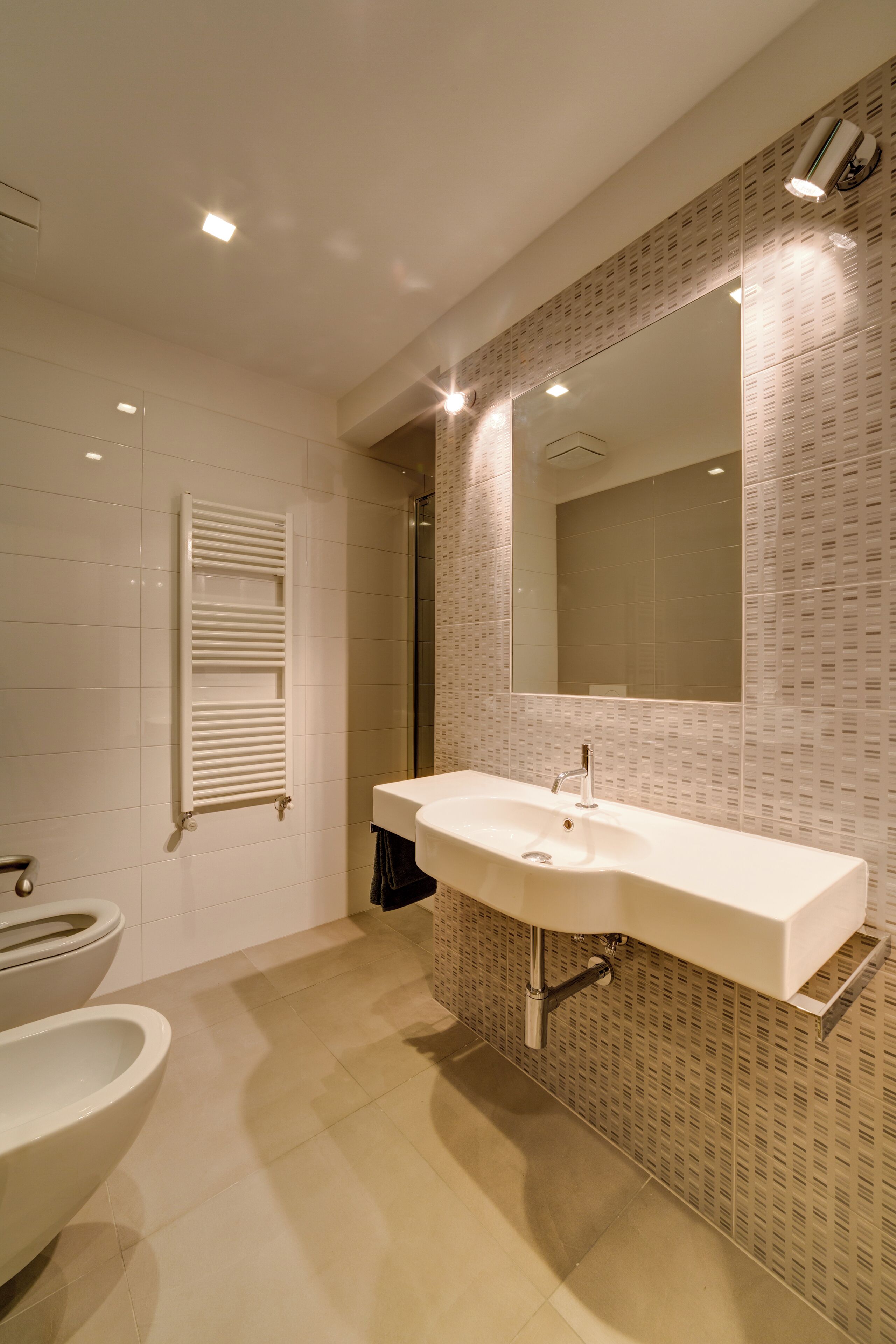 Une salle de bain moderne avec un lavabo blanc, un miroir et des toilettes.