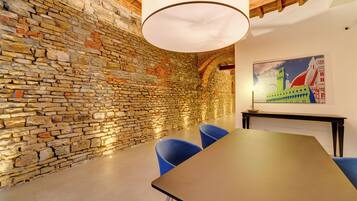 A conference room with a stone wall, a wooden ceiling, and a table with chairs.