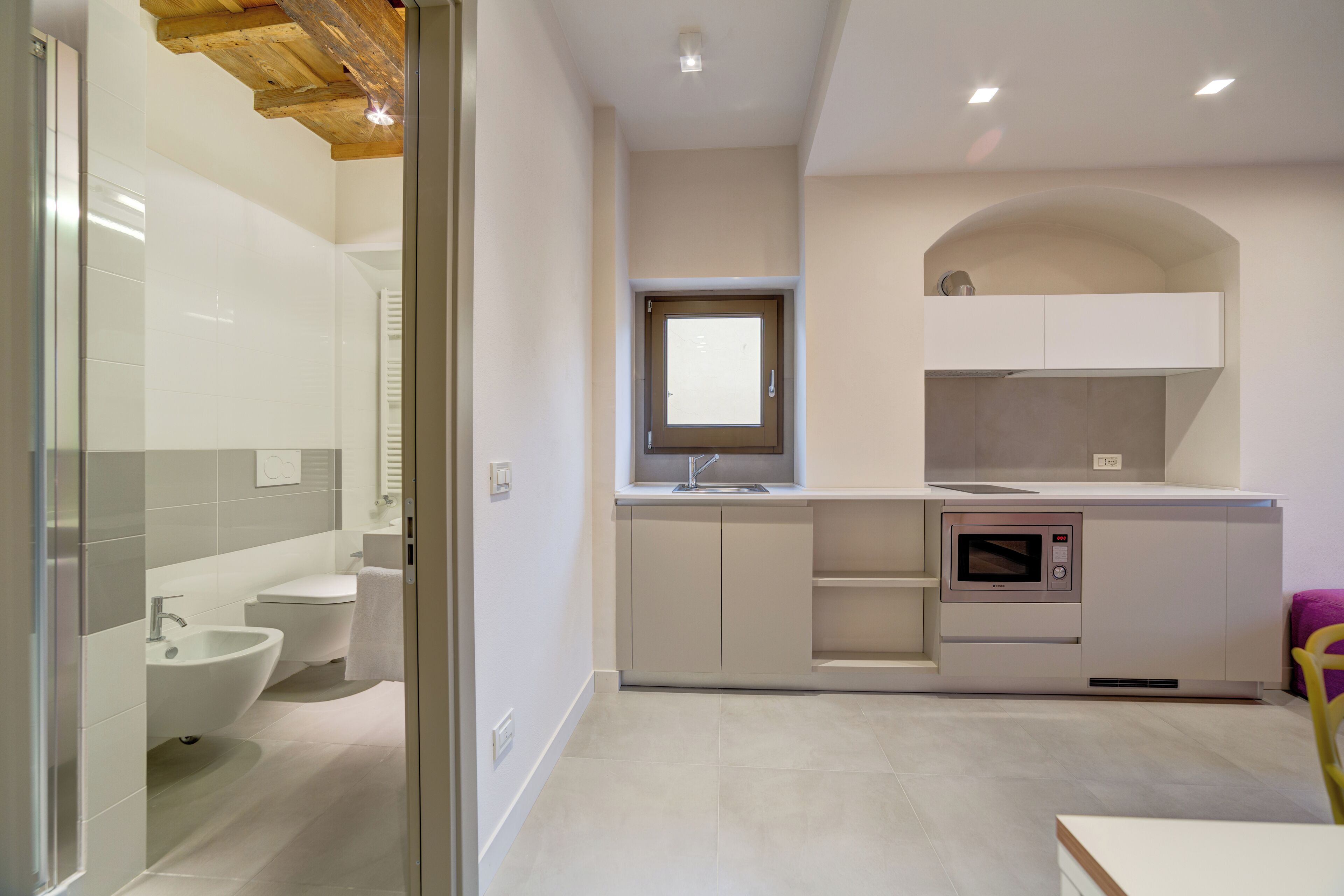 Eine moderne Küche mit eingebauter Mikrowelle, einem Fenster über der Spüle und einem kleinen Fenster über dem Backofen.