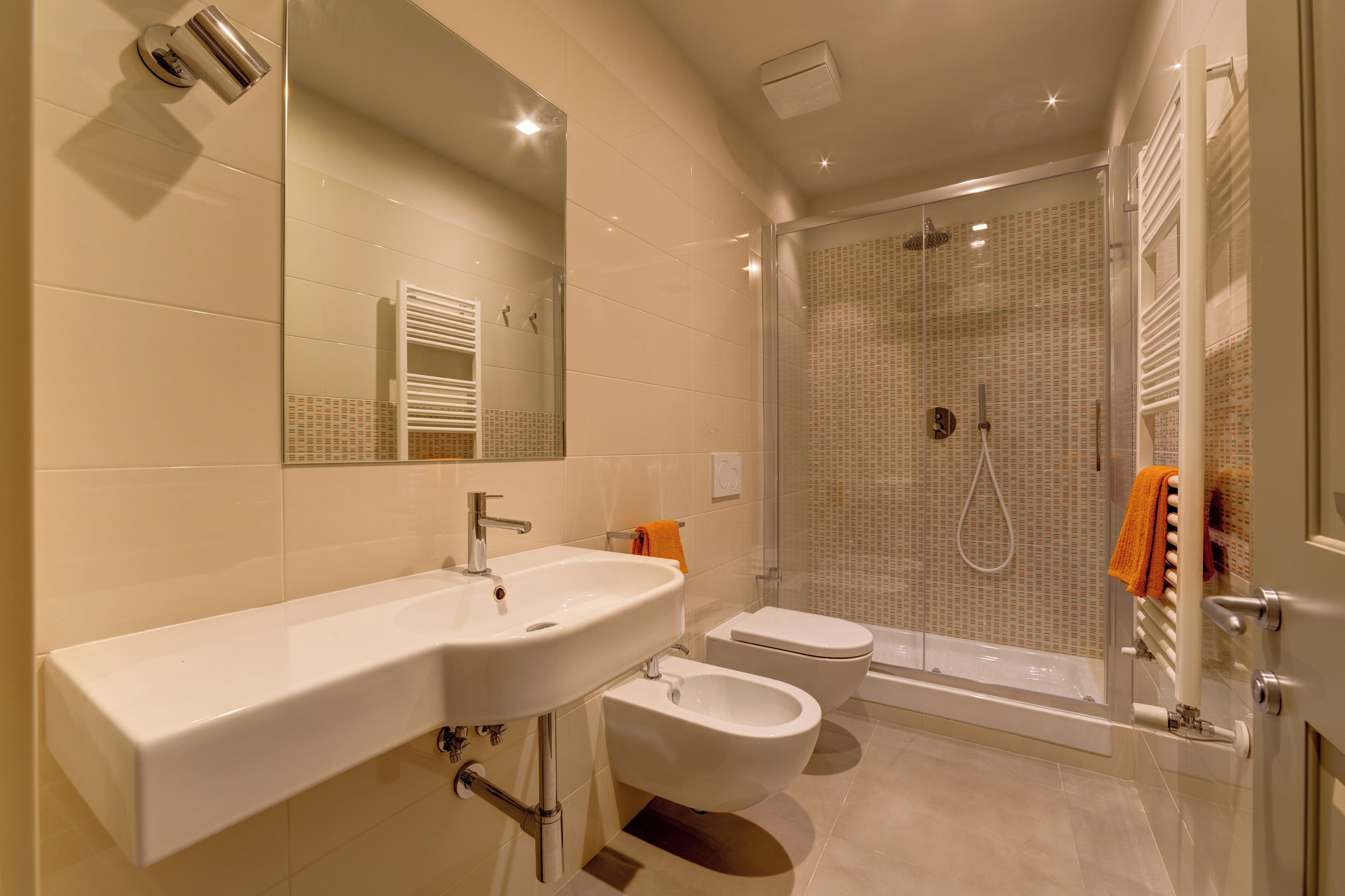 Une salle de bain moderne équipée d’un lavabo, d’un bidet, de toilettes et d’une douche à l’italienne.