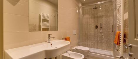 Une salle de bain moderne équipée d’un lavabo, d’un bidet, de toilettes et d’une douche à l’italienne.