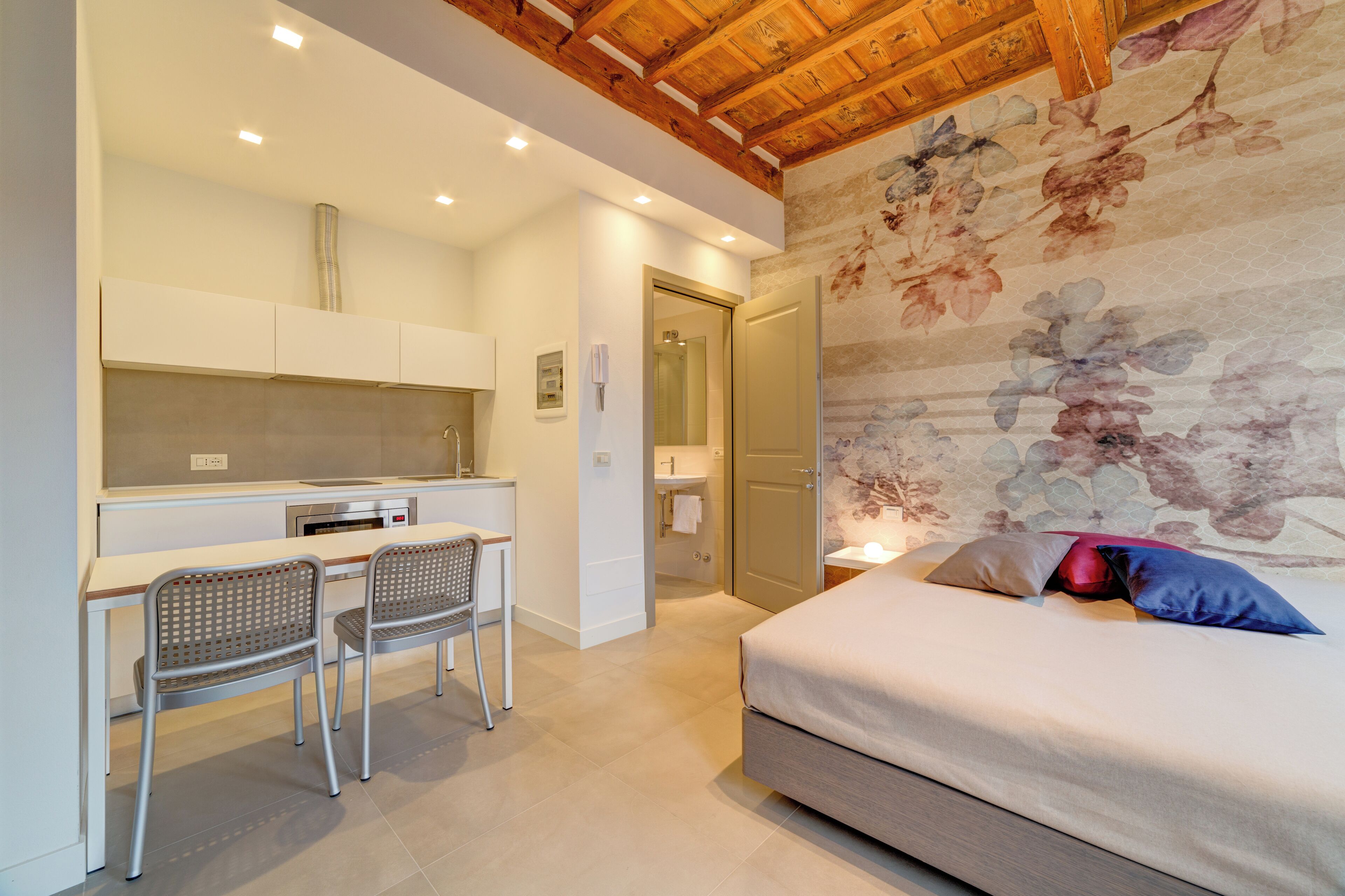 Ein Schlafzimmer mit Bett, Schreibtisch mit zwei Stühlen, einer Küchenzeile und einem Badezimmer.