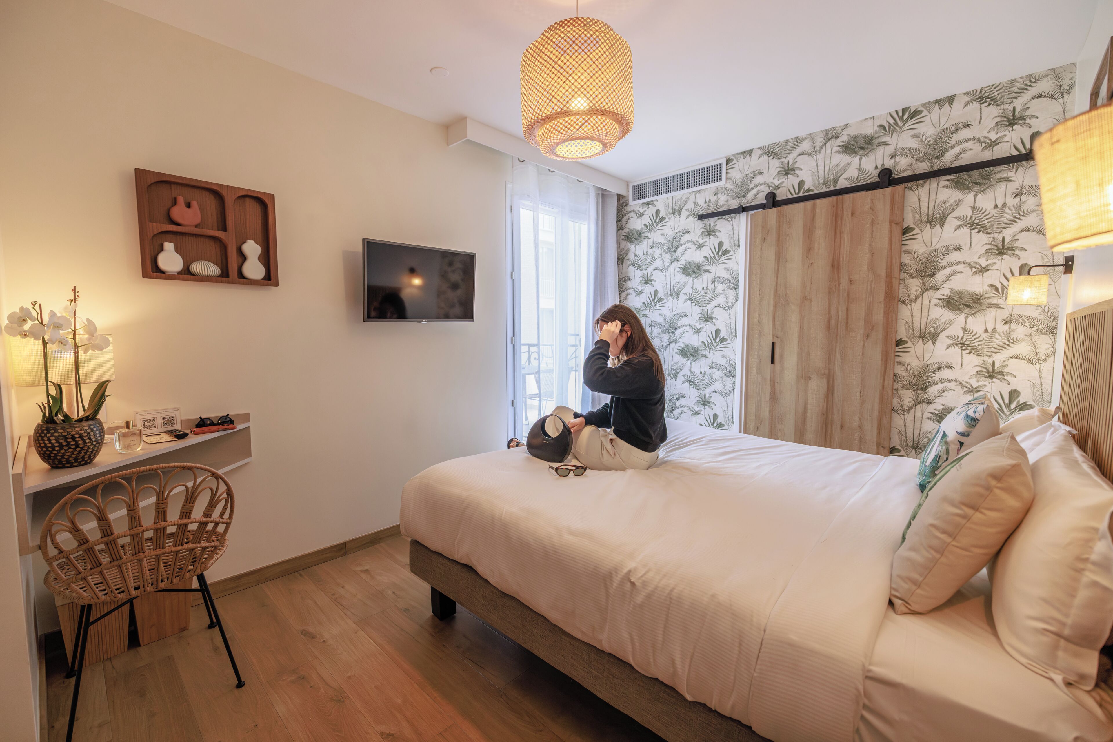Un dormitorio con cama, escritorio, silla, televisor y puerta corrediza.