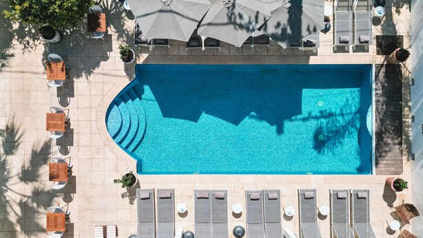 An aerial view of a swimming pool area with lounge chairs, umbrellas, and potted plants. - Hotel La Villa Juan Beach (Antibes)