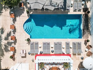 Vue aérienne d’un espace piscine avec des chaises longues, des parasols et des plantes en pot.