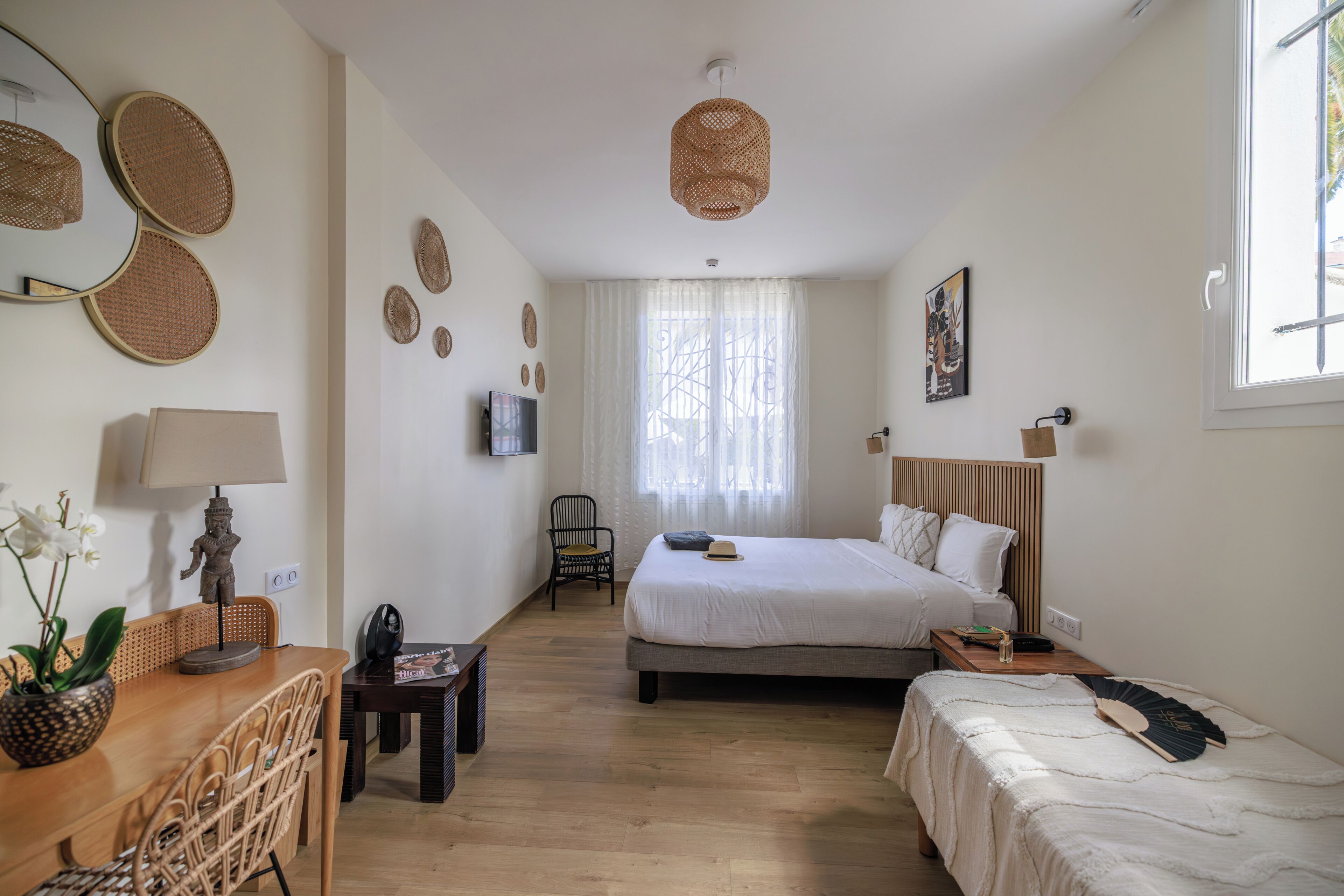 A hotel room with a bed, a desk, a chair, a television, and a window with curtains.