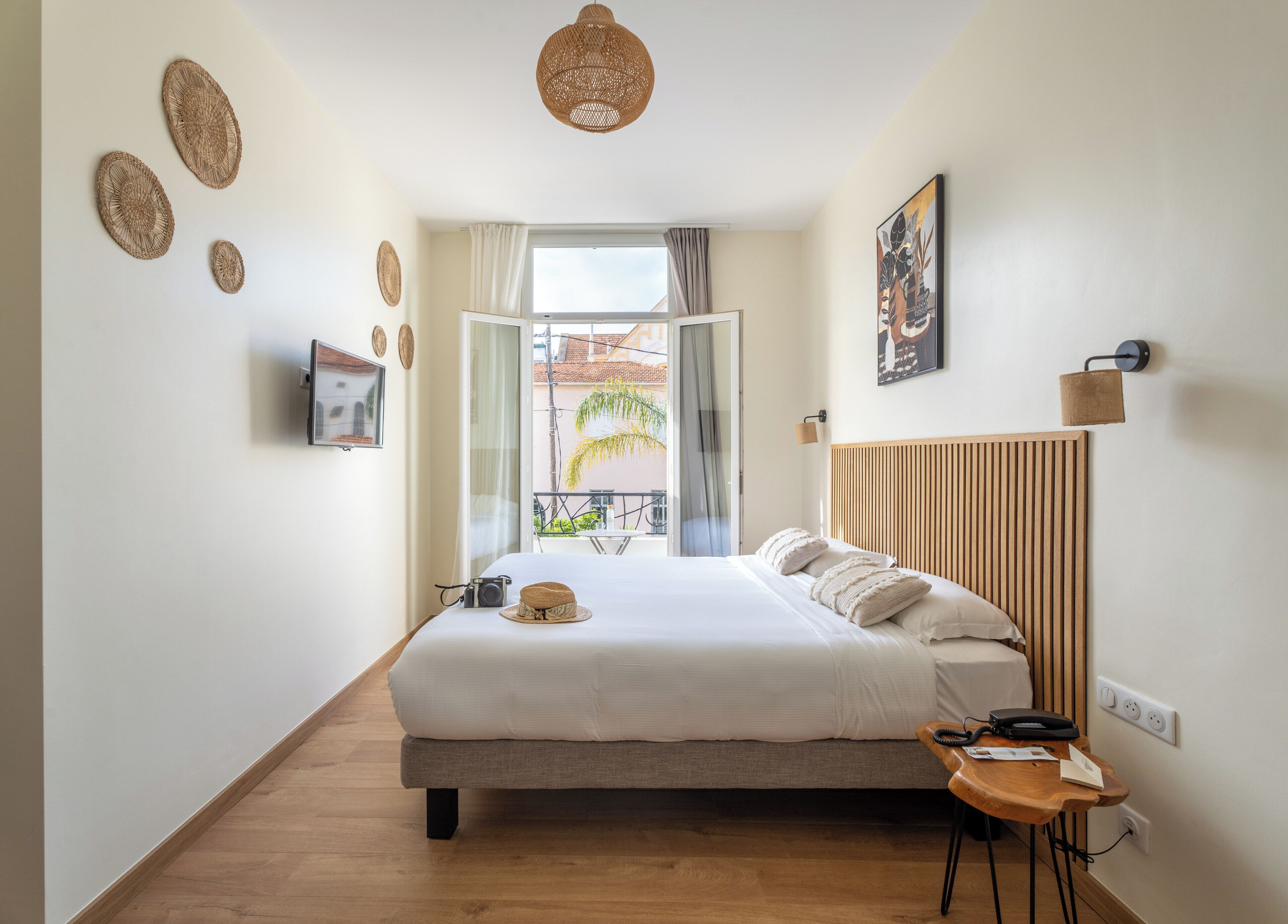 A modern bedroom with a bed, bedside table, and a view of the outside.